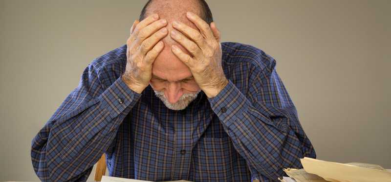 Frustrated man looking at financial papers.