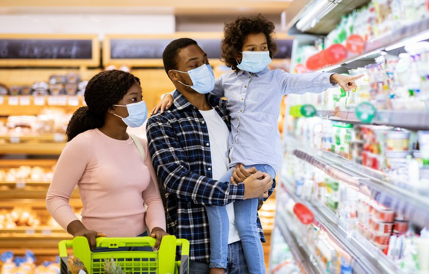 Two adults and a child wearing masks and grocery shopping.
