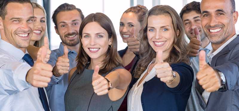 Group of professionally dressed adults giving thumbs up.
