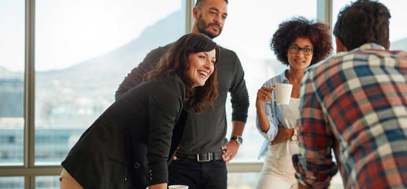 Group of young adults standing around a table interacting.