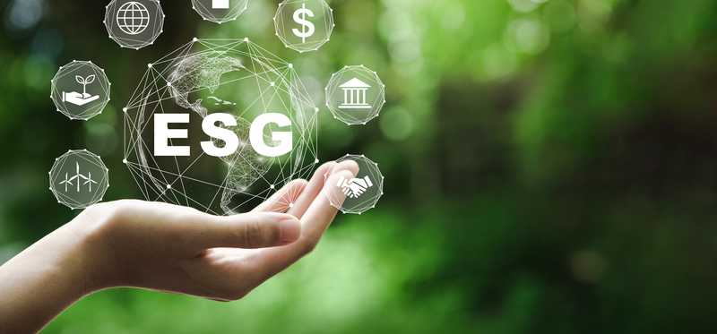 A hand holding a projected globe with the letters ESG written across it and various ESG icons..