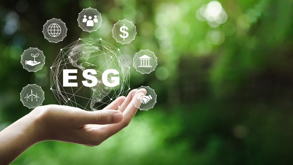 A hand holding a projected globe with the letters ESG written across it and various ESG icons..