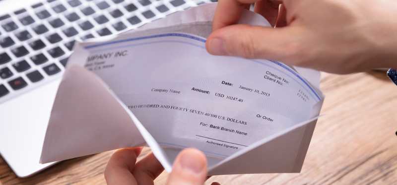 Hands opening check in envelope
