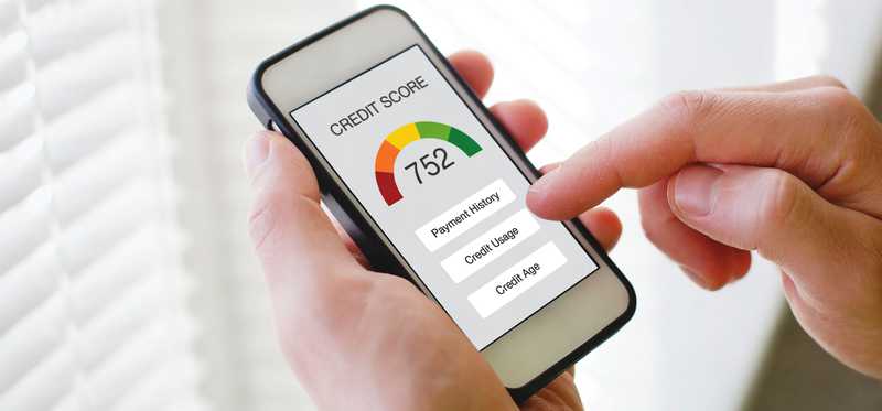 A hand and a phone showing a credit score.
