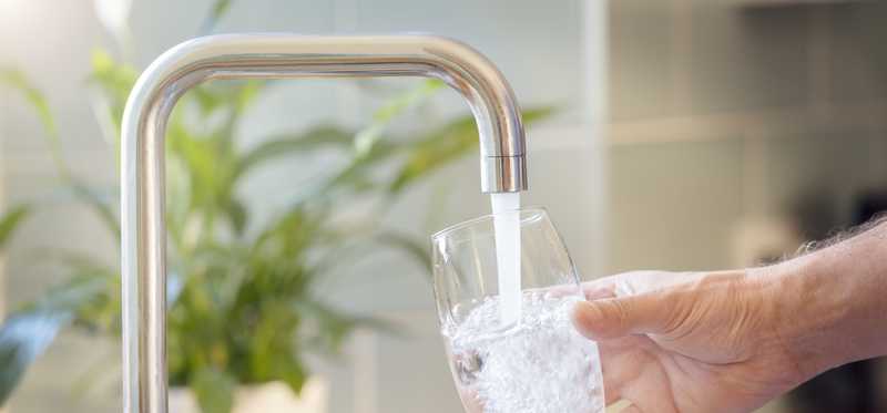 A person getting a glass of water at a sink.