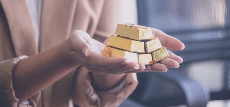 Hands holding pile of gold bars