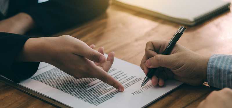 Two pairs of hands engaged in signing a contract.