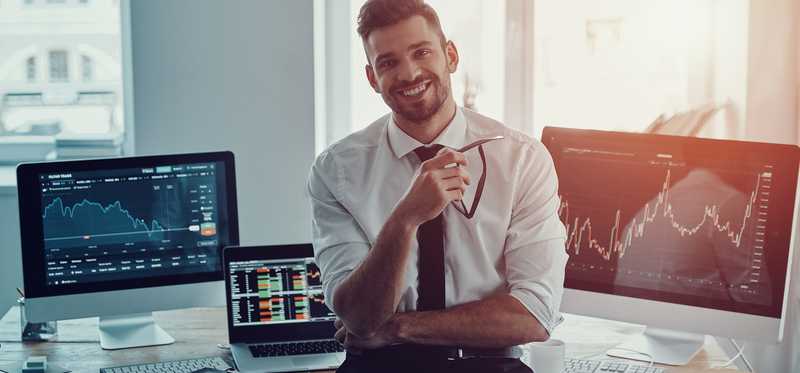 Person raises arms in success in front of computers.