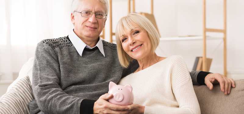 Two people embrace while holding piggy bank.