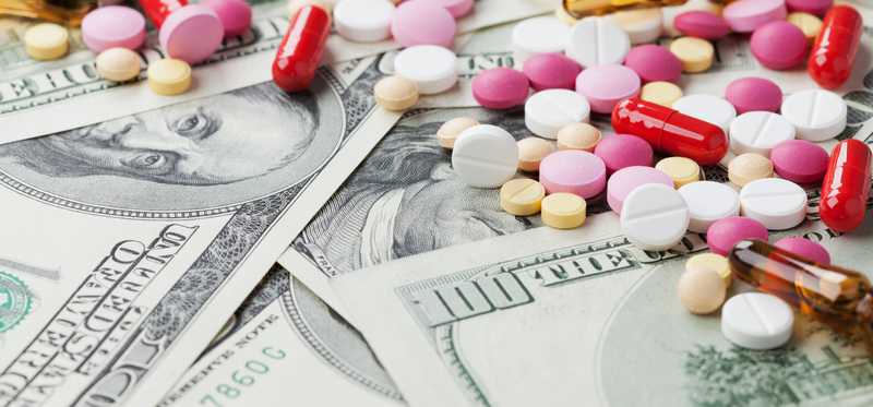 Hundred dollar bills with pill spread on top.