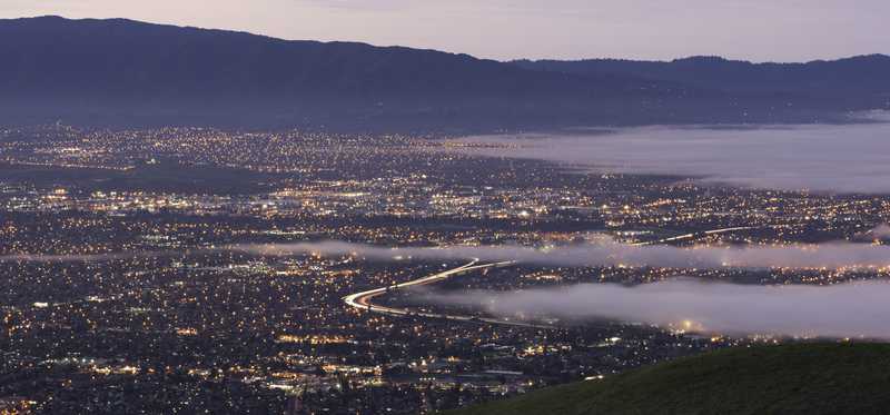 A high valley shot of San Jose, California, at dawn, with clouds hovering over parts of the city.