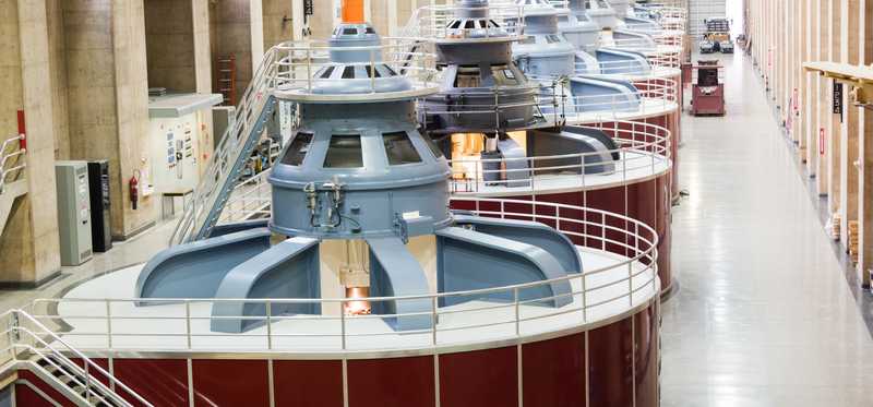 A row of huge industrial turbines in a building.