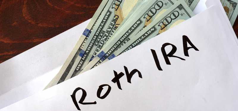 hundred dollar bills sticking out of envelope with Roth IRA written on it