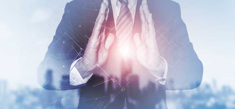 Digital image of man over a cityscape with a light orb between his hands.