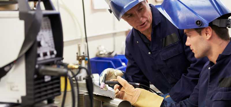 Two people working at an industrial bench.