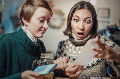 Two people looking shocked at a receipt.