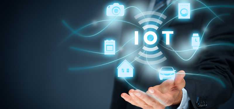 A businessman with hand outstretched and a graphic floating above his palm with the letters IOT.