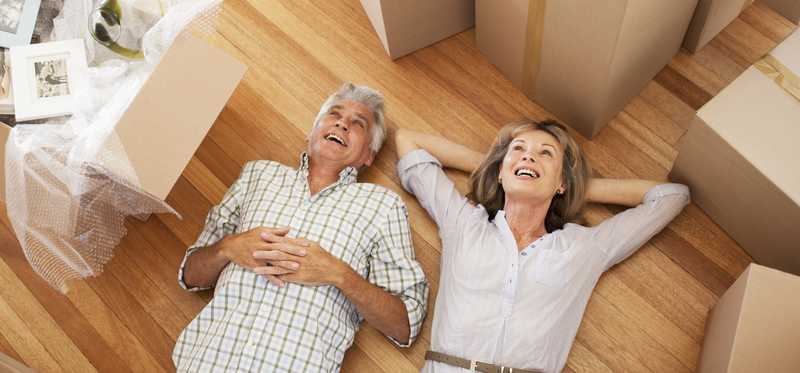 Two people lying on a floor among boxes and taking a break during a move.