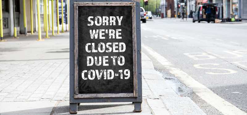 Chalkboard outside business reading "Sorry we're closed due to COVID-19"