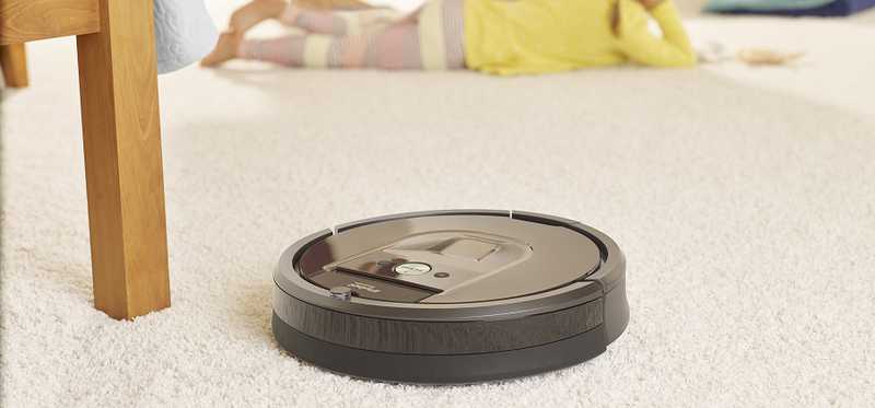A Roomba sits in a carpeted room.