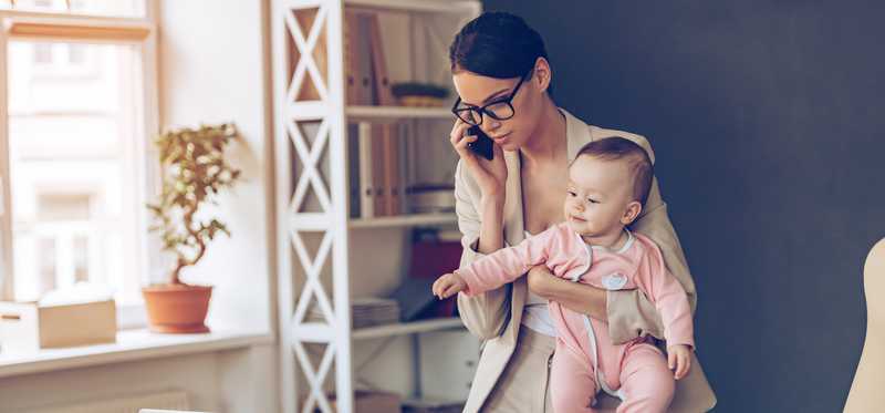A person holds a child while talking on the phone.
