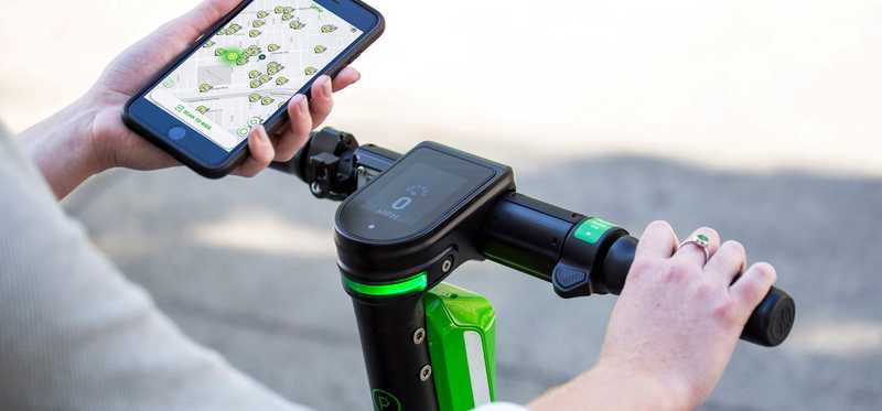 A person using their smartphone to rent a Lime scooter.