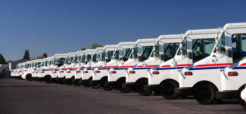 A line of U.S.P.S. mail home delivery trucks.