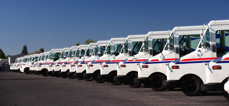 A long line of United States Postal Service trucks.