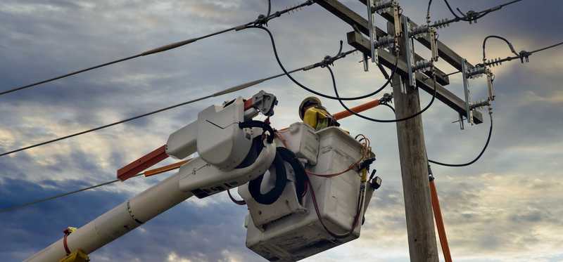 A lineman in a cherry picker working on power lines.
