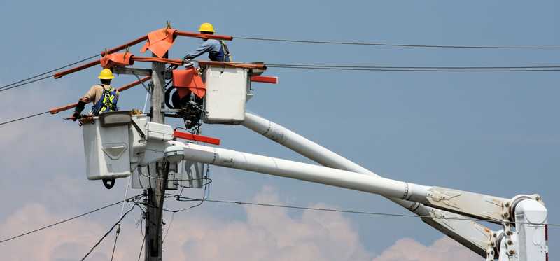 Linemen working on power lines above the ground.