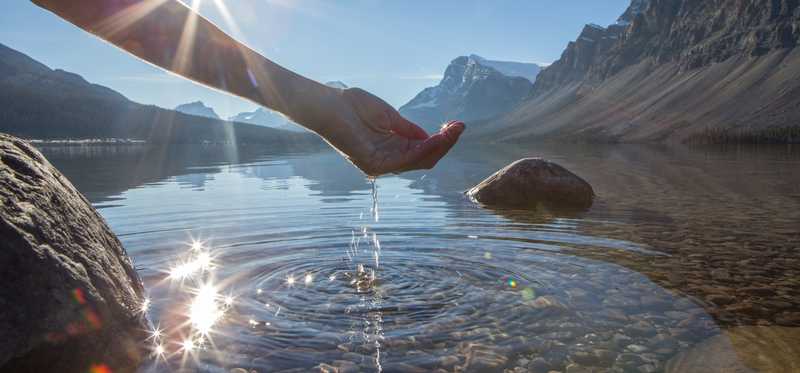 A hand cupping water from a lake.