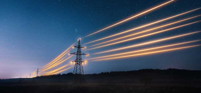 Lit-up power lines between big power towers.