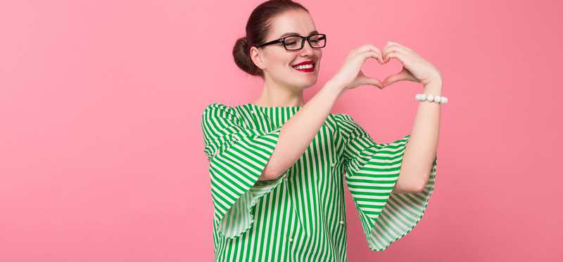 A woman makes the heart symbol with her hands.