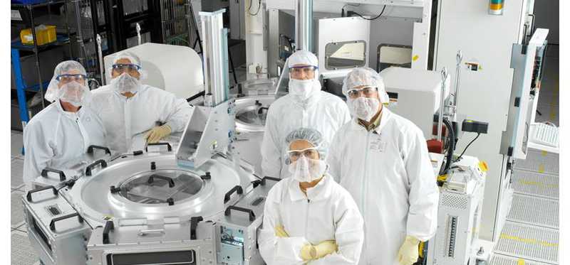Semiconductor workers pose for a picture in a clean room.