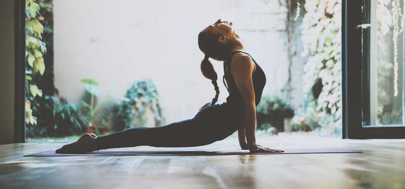 Woman doing yoga in leggings and tank top.