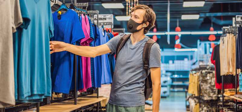 Man wearing mask shopping for clothes