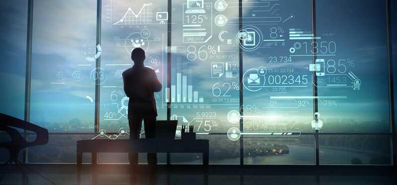 Man standing in front of windows covered in data.