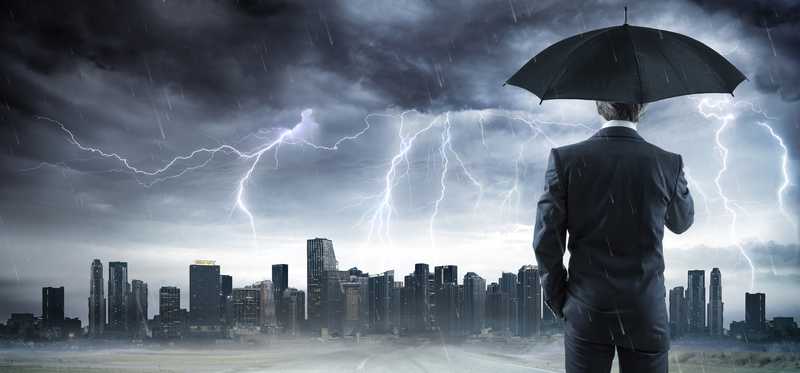 Person holds an umbrella during a storm near a cityscape.