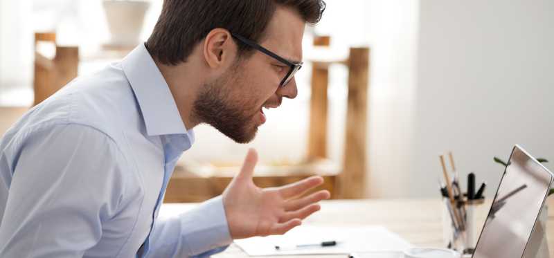Frustrated man yelling at laptop