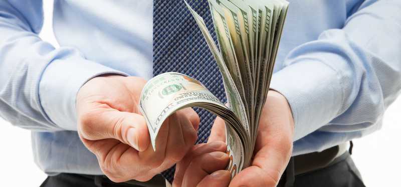 Person's hands flipping through wad of bills.