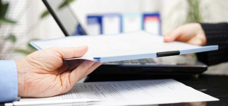 Person handing over a document.