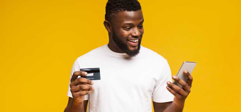 Smiling man holding credit card and cell phone