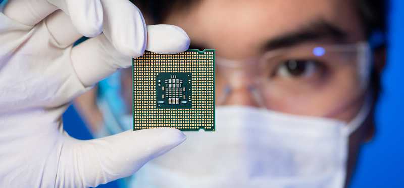 Gloved and masked man holding microchip