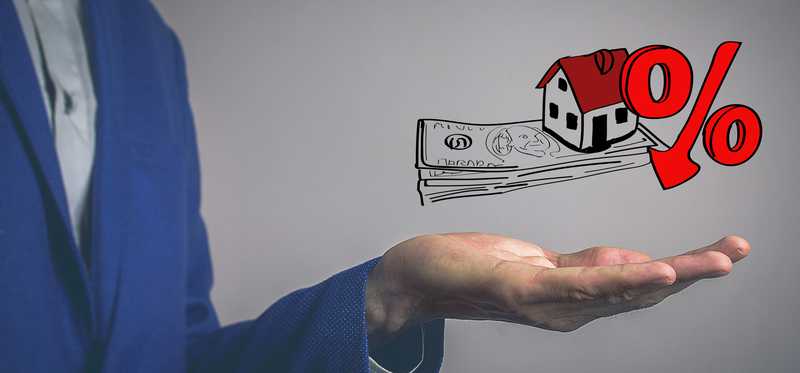 Person holding their hand open below an illustration of a house and a percentage symbol on top of money.