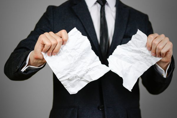 man in business suit tearing piece of paper in half
