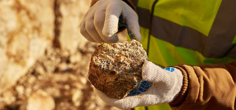 Man in safety vest holding a rock.