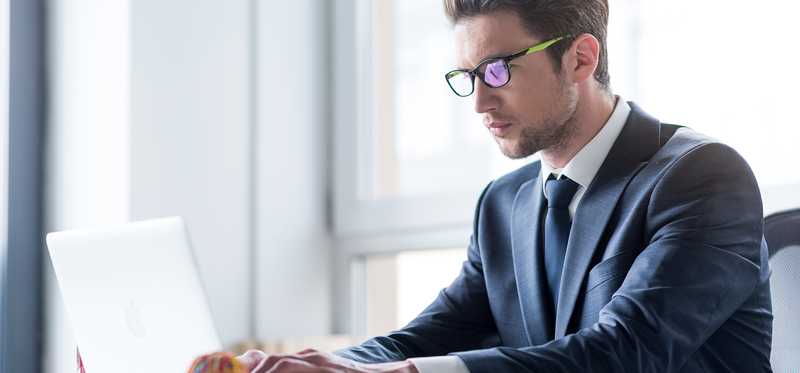 Person sitting at desk and typing on a laptop.