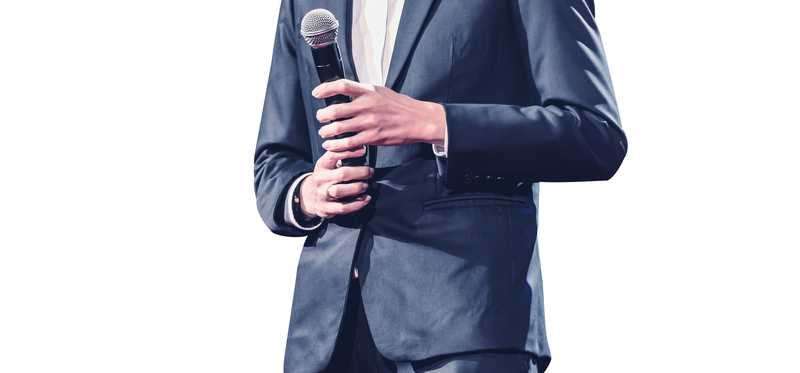 Man in suit holding a microphone.