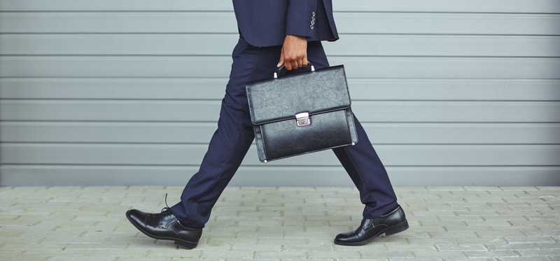 Man in suit carrying a briefcase while walking.