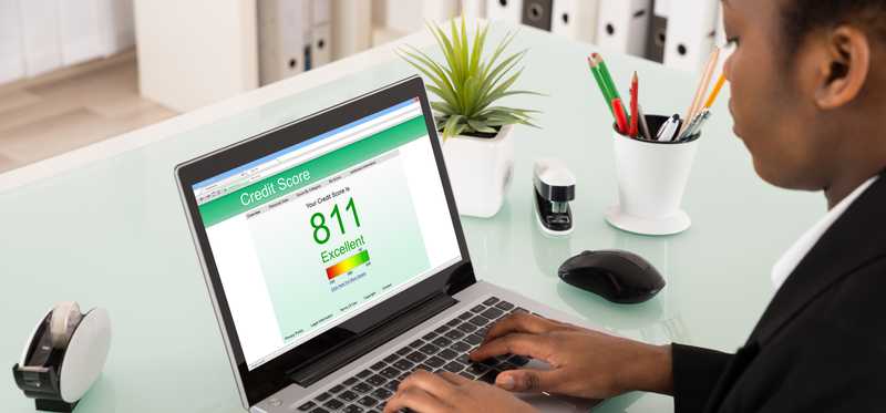 A person with a laptop showing a credit score.
